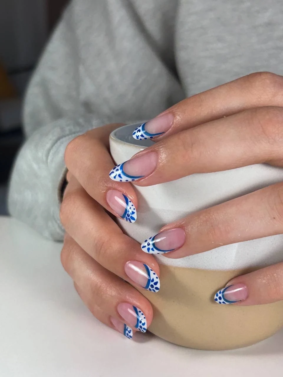 Blå-hvidt porcelænsinspireret French-negledesign omkring en keramikkop hos Marzieh Nail Atelier